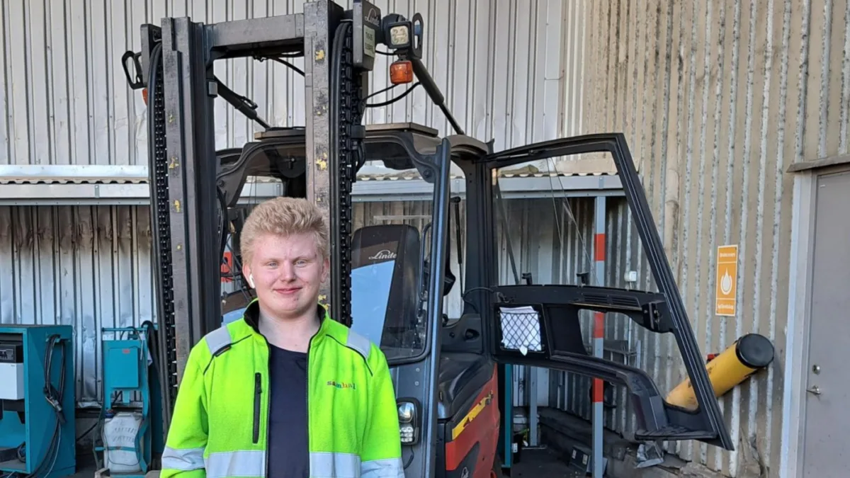 Gustav står framför en truck. Han ler och tittar in i kameran.