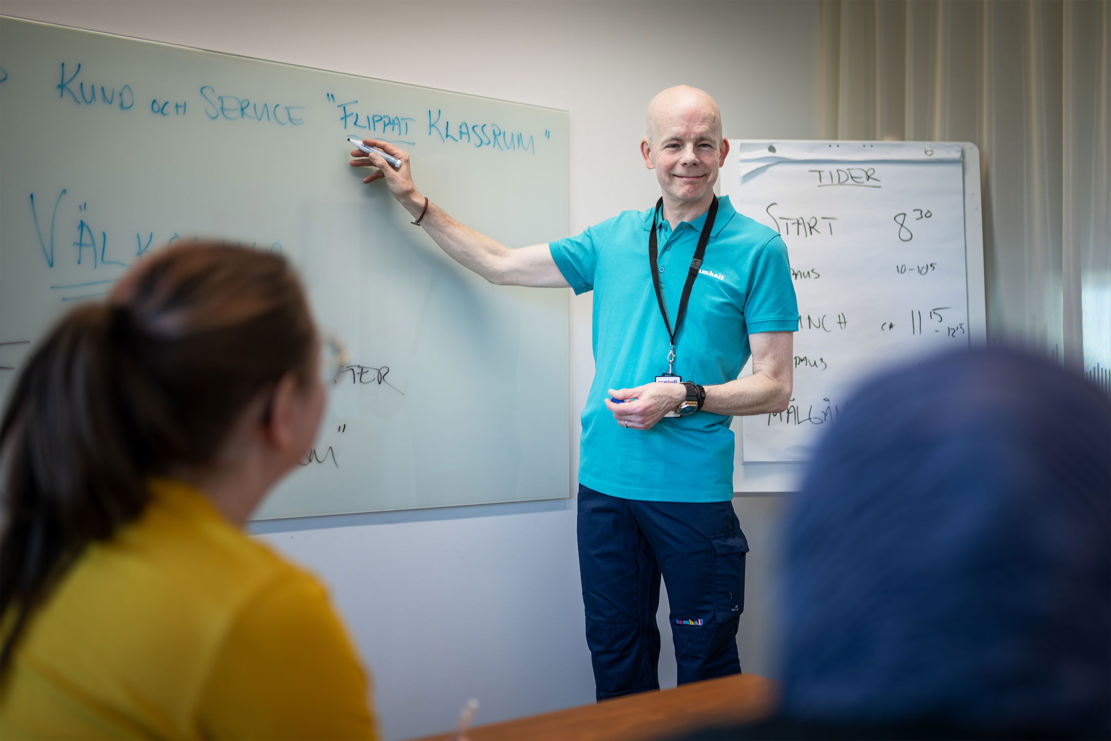 En medarbetare leder en utbildning och skriver på en whiteboard medan kollegor lyssnar.