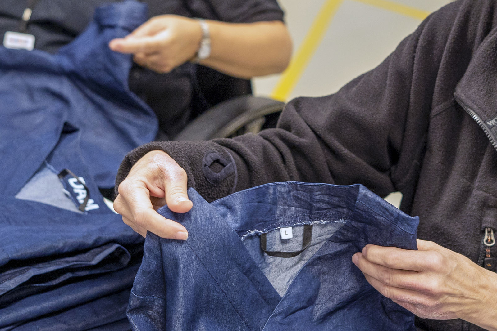 En Samhallsanställd som håller klädesplagg i sina händer.