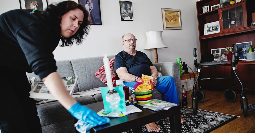 Monika Nilsson torkar med en trasa på vardagsrumsbordet hemma hos Mikael Taskinen.