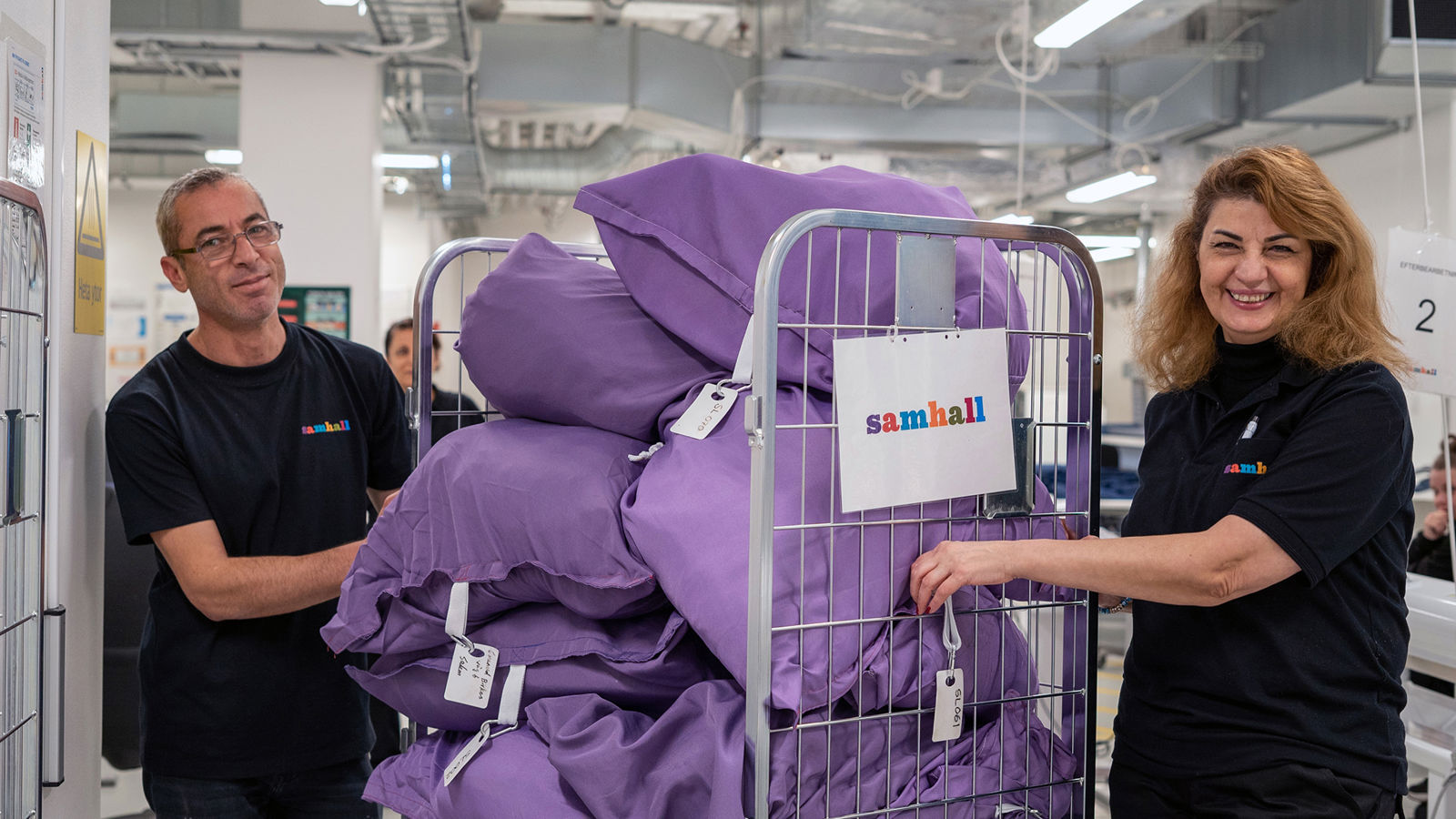 En man och en kvinna står vid sidan av en vagn med lila tvättpåsar.