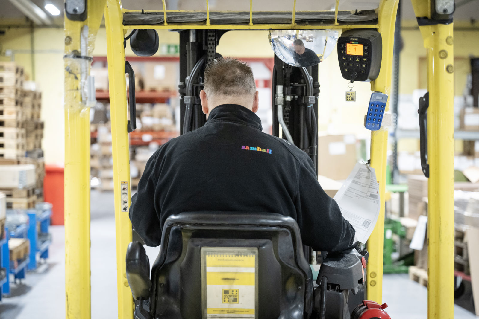 En man sitter i en gaffeltruck i en lagerlokal.