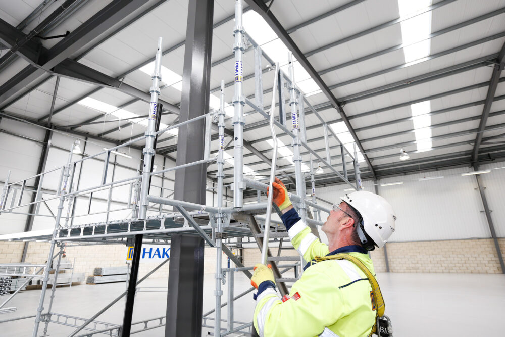 Person med arbetskläder bygger en ställning.