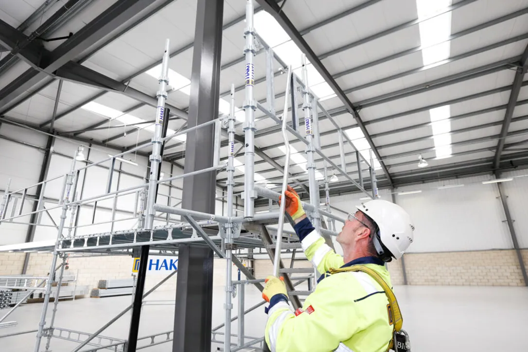 Person med arbetskläder bygger en ställning.