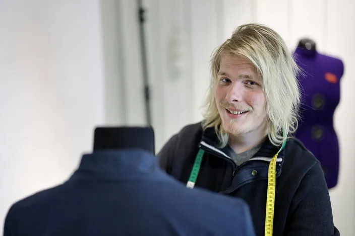 Porträtt på Nicklas Carlsson som hänger kläder på en provdocka.