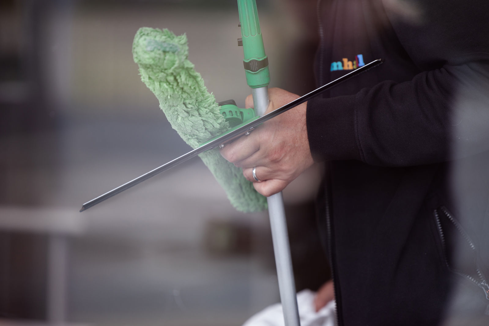 En samhallmedarbetare som håller i redskap för tvätt av fönster.