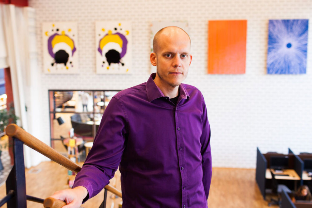 Man med rakat hår och lila skjorta i en trappa i en kontorsmiljö.