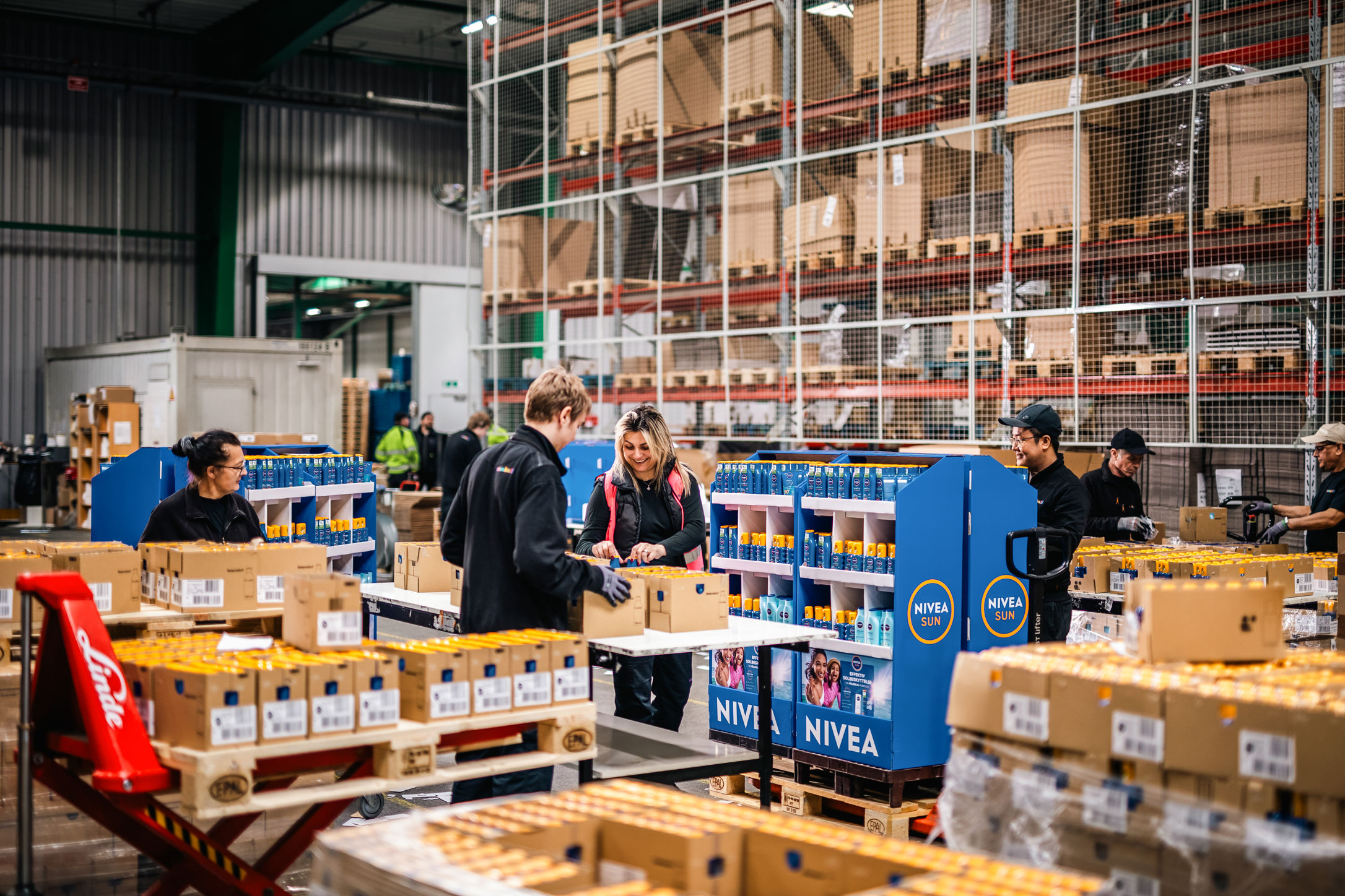 Samhallsanställda som packar solkräm i en lagerlokal.