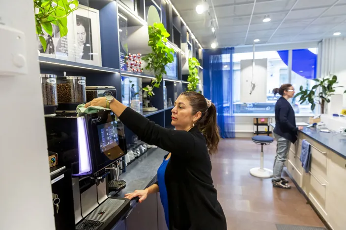 Medarbetarna Luz Mary Grueso Villada torkar en kaffemaskin med en trasa i ett kök.