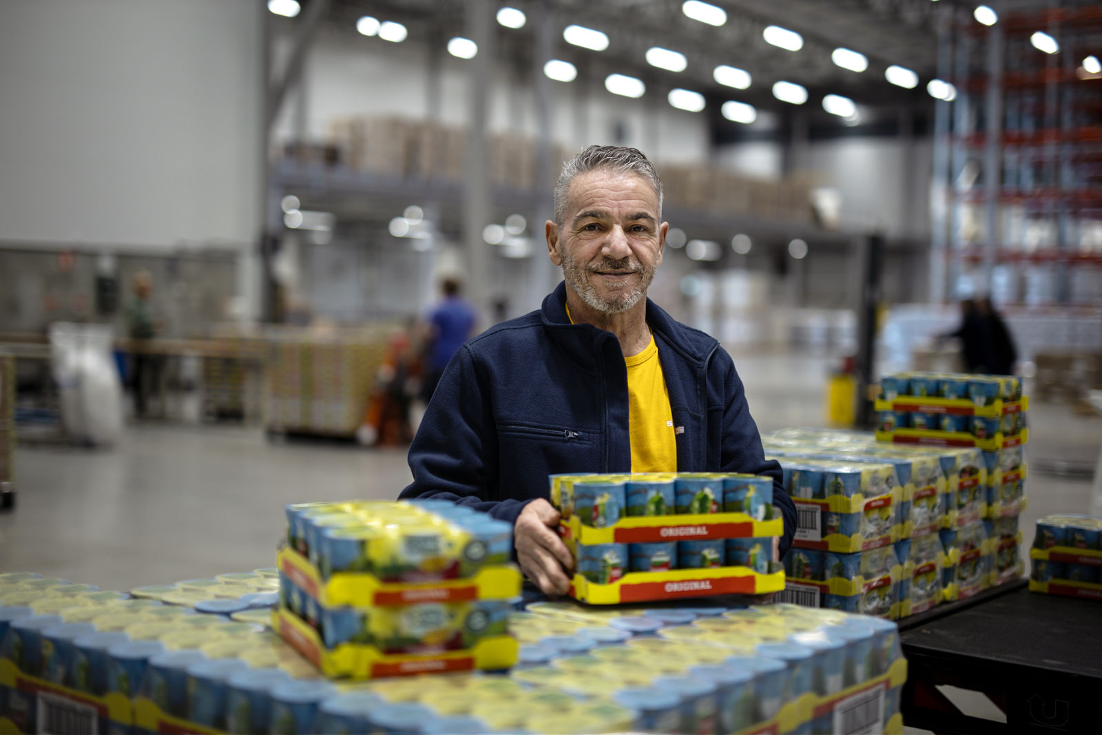 Samhallsmedarbetare hanterar varor i en lagermiljö.