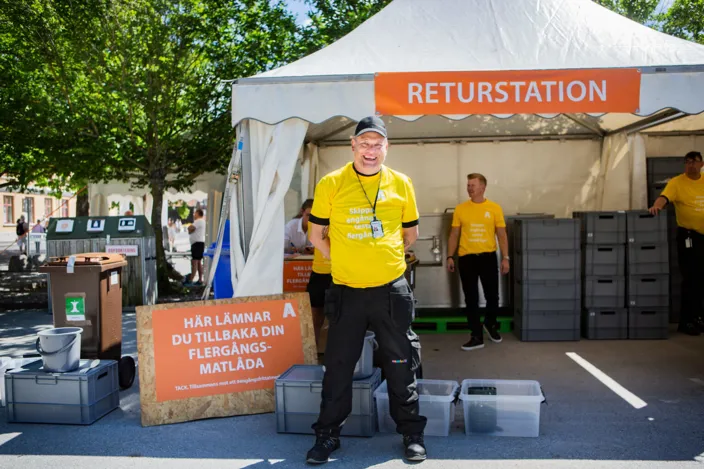 En person står utanför ett partytält i Almedlen och tittar in i kameran och ler. Han bär svart keps och gul T-shirt. 
