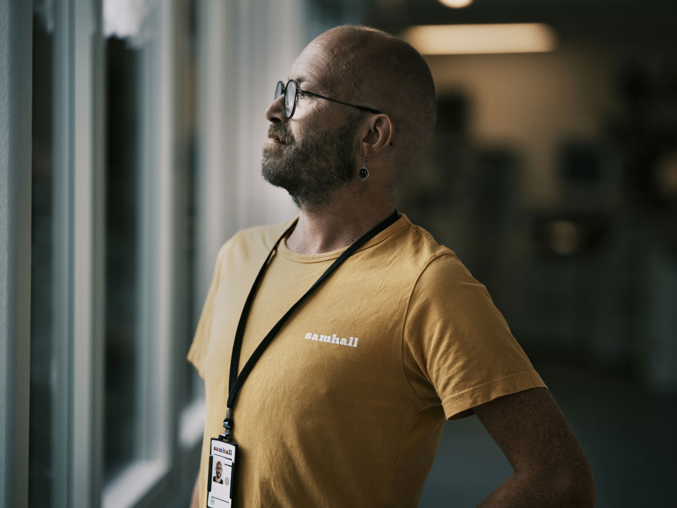 En Samhallmedarbetare står vid ett fönster och tittar ut.