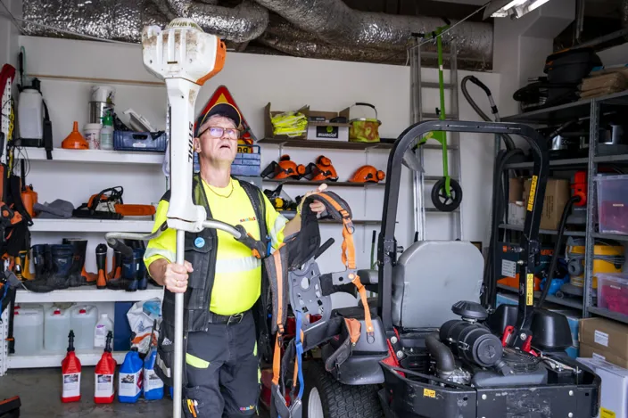 Bild av Mats Fundin som står i ett garage och håller i trädgårdsredskap.